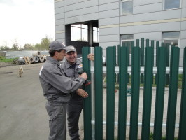 Бригадиры Владимир и Петр монтируют штакетный забор
